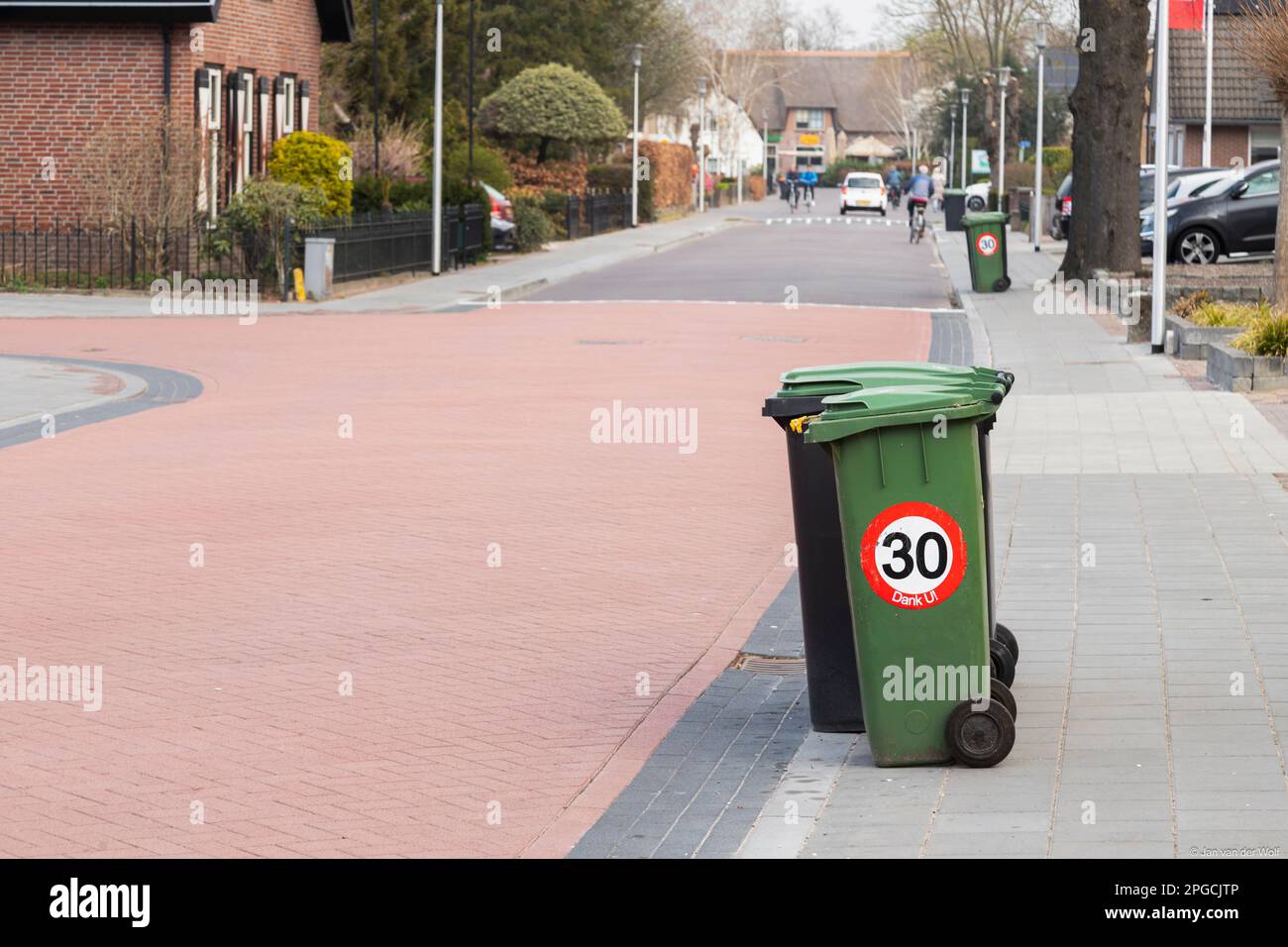Müllcontainer auf der Straße mit einem geschwindigkeitsbegrenzenden Straßenschild von bis zu 30 km/h. Stockfoto