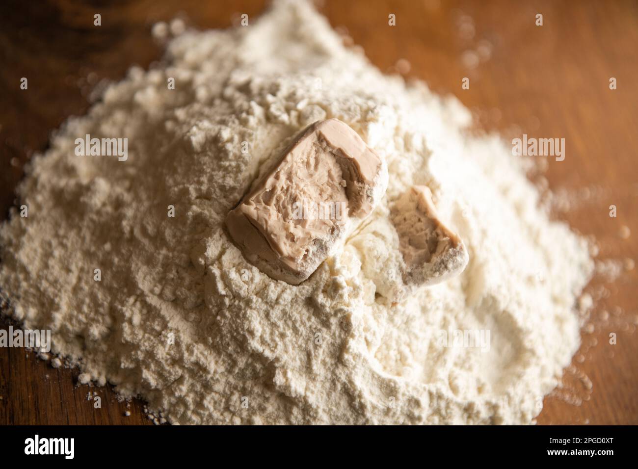Ein Würfel Hefe zerbröckelte auf dem Mehl Stockfoto
