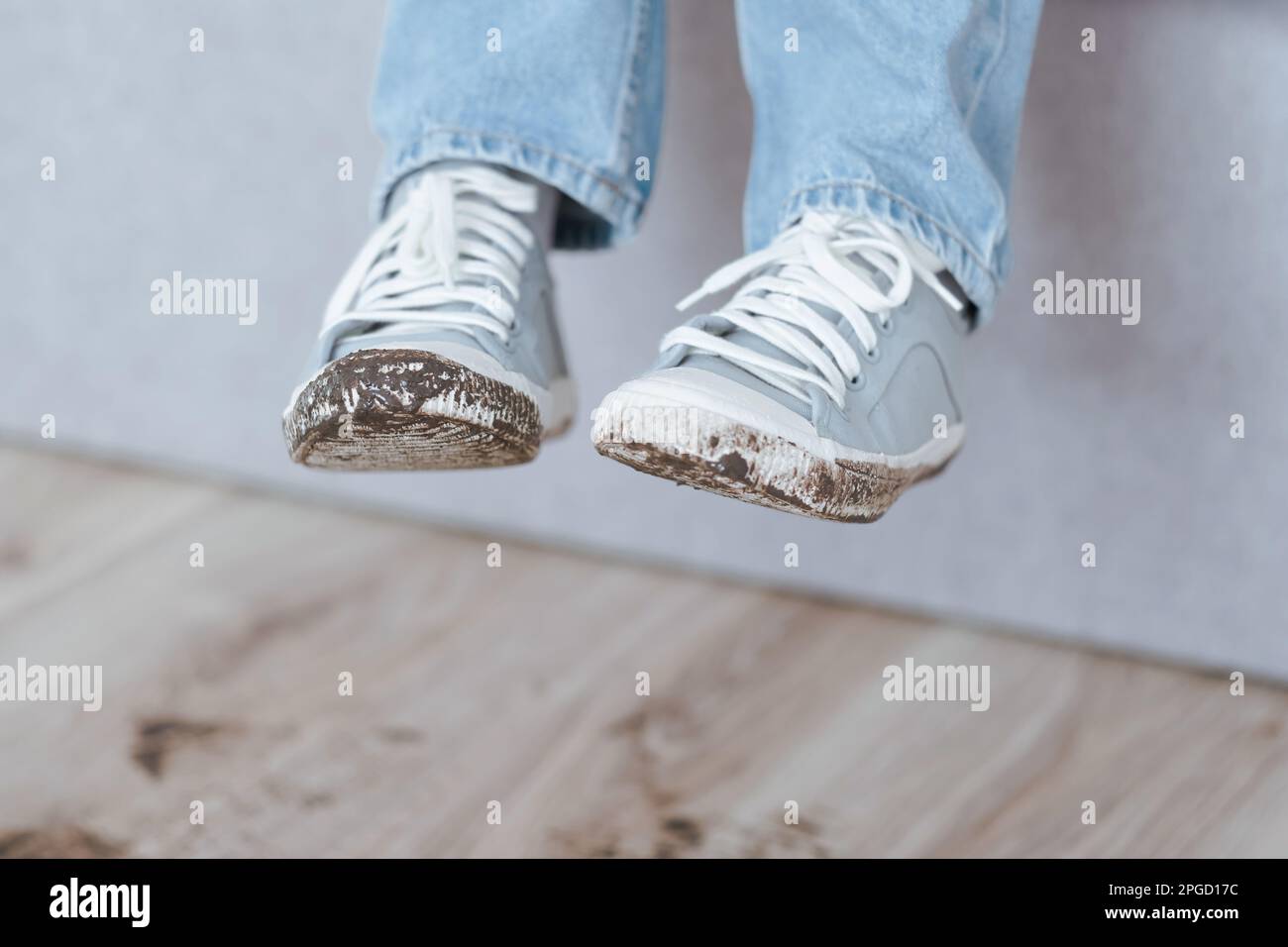 Eine Person, die schmutzige Schuhe trägt. Verdorbene Schuhe. Schlammabdruck auf dem Boden. Täglich schmutziger Fleck. Stockfoto