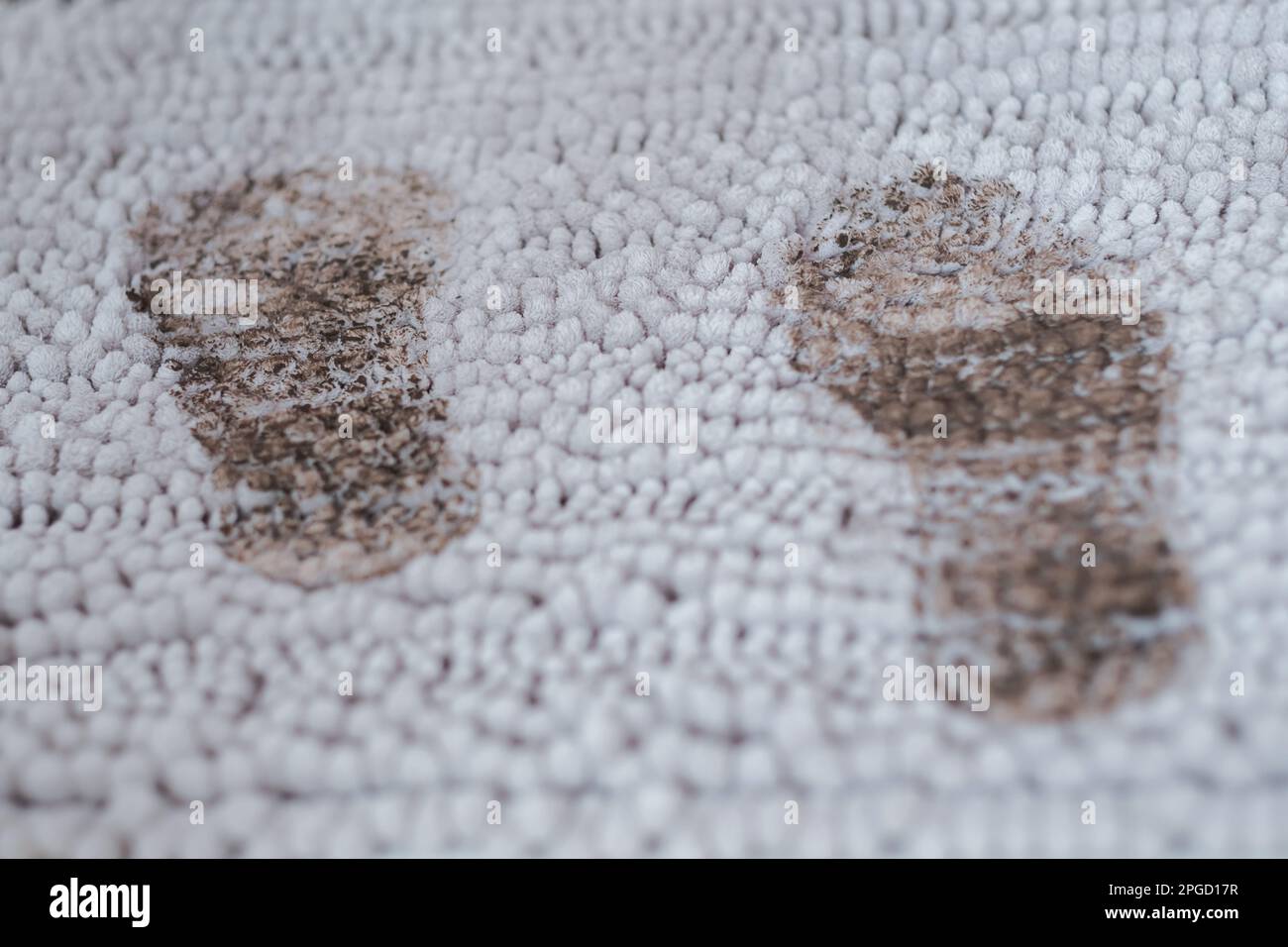 Spuren von schlammigen Fußabdrücken auf grauem Teppich. Täglich schmutziger Fleck. Stockfoto