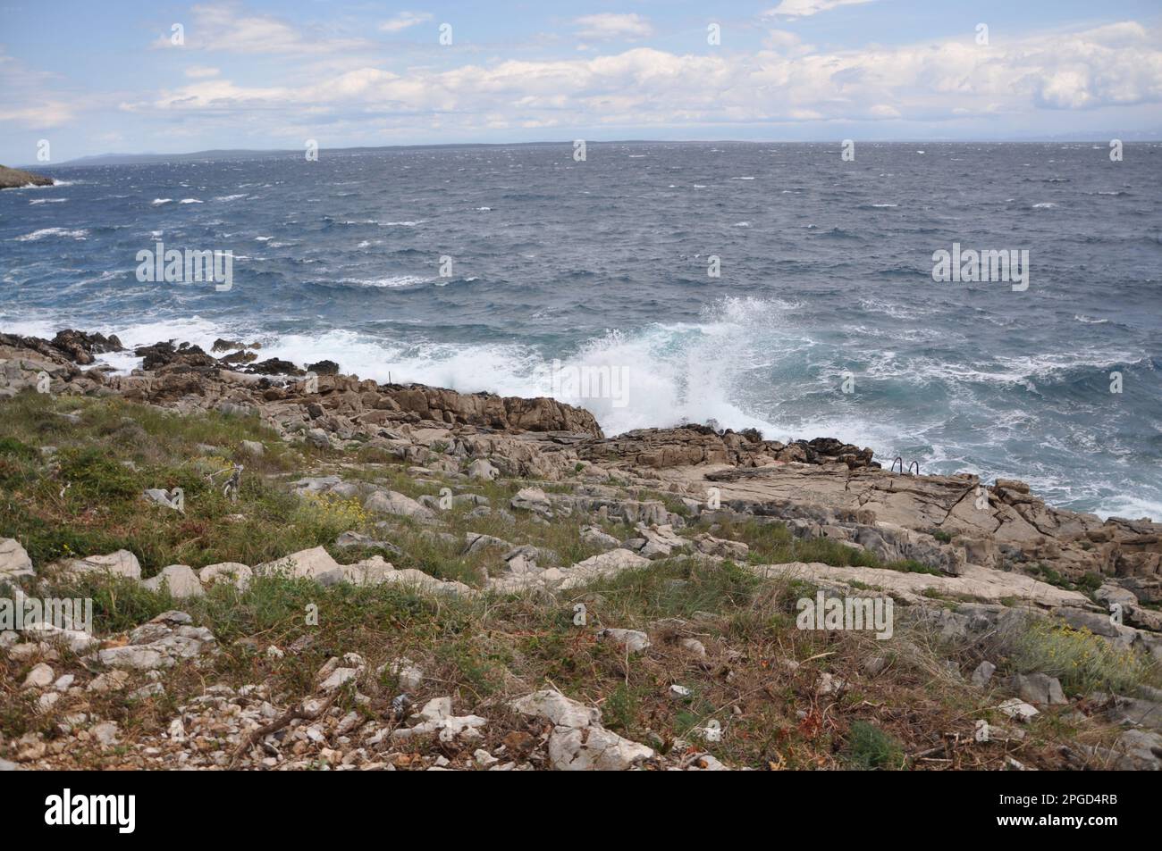 Die Meereswelle stürzt auf den Felsen und lässt das spritzwassernde Wasser und den weißen Luftschaum blasen. Stockfoto