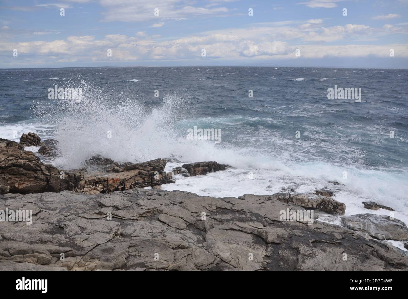 Die Meereswelle stürzt auf den Felsen und lässt das spritzwassernde Wasser und den weißen Luftschaum blasen. Stockfoto