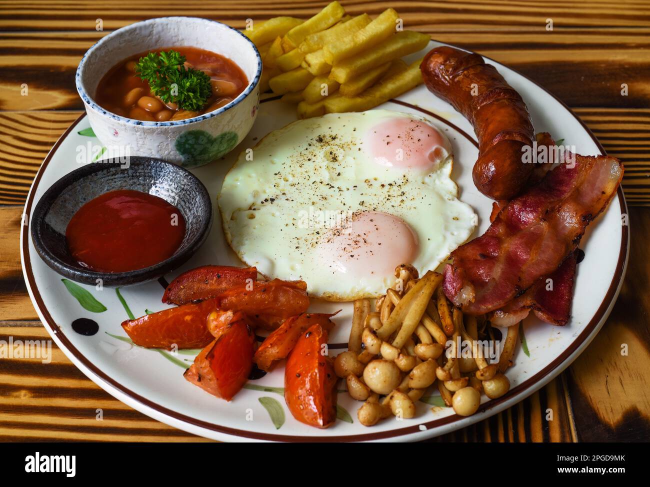 Gesundes englisches Frühstück mit Spiegeleiern, Würstchen, Speck, pommes frites, Bohnen und Tomaten in der Nähe Stockfoto