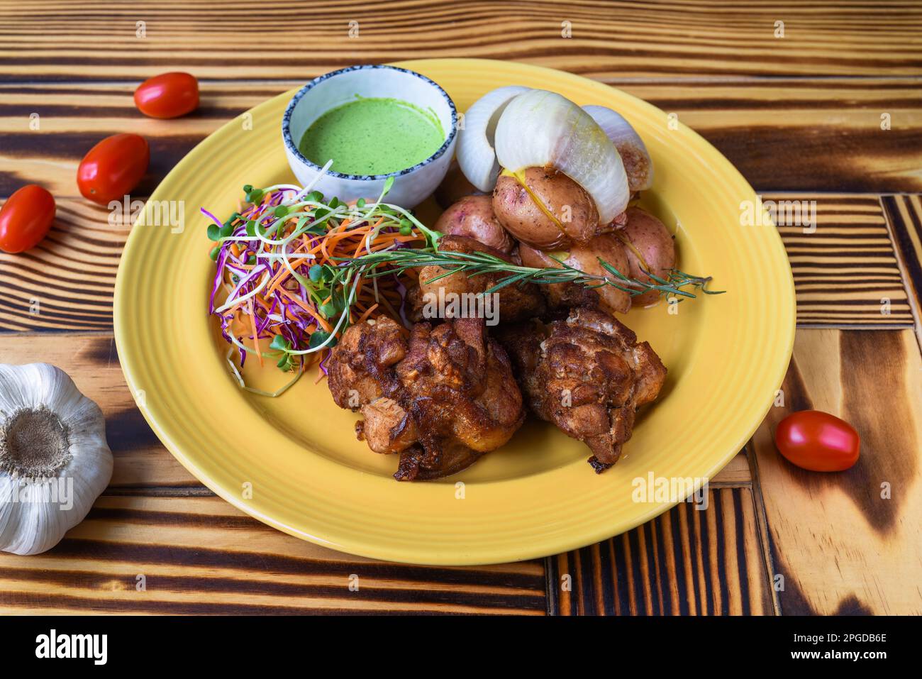 Peruanisches Huhn mit grüner Sauce und Salat mit Kartoffeln auf gelbem Teller, Nahaufnahme der Seite Stockfoto