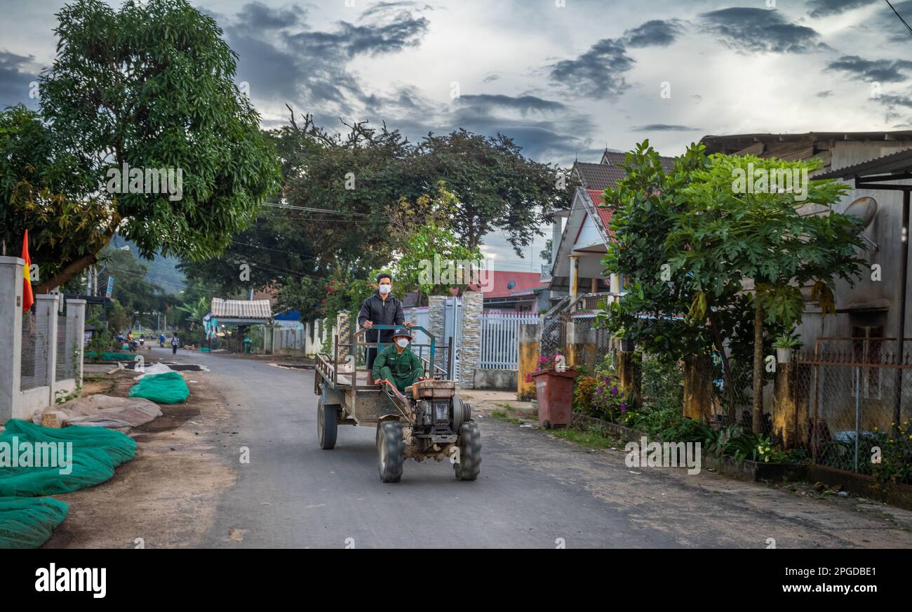 Zwei Männer aus der ethnischen Minderheit der Mnong fahren auf einem zweirädrigen Traktor und Anhänger und kehren am Ende des Tages nach Buon Jun, Lien Son, Vietnam, zurück. Stockfoto