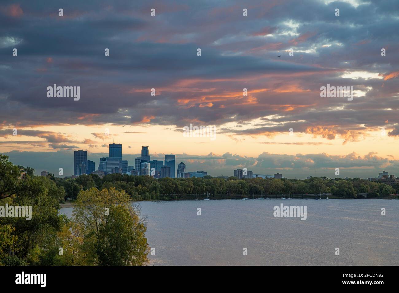 Der Sonnenaufgang färbt die Morgenwolken orange über Minneapolis und Lake Calhoun in Minnesota. Stockfoto