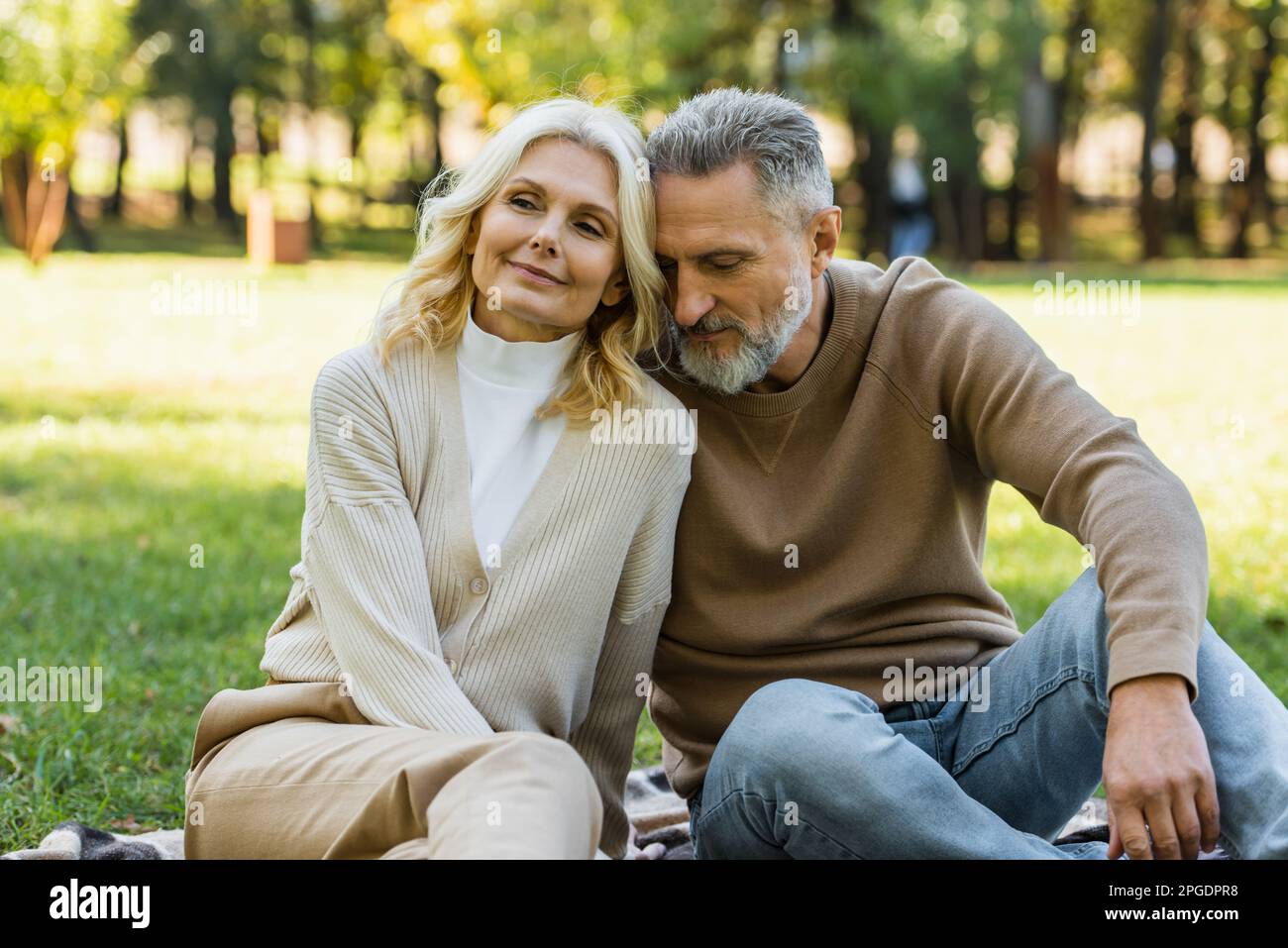 Porträt eines charmanten Paares mittleren Alters, das im Frühling im Green Park sitzt, Stockbild Stockfoto