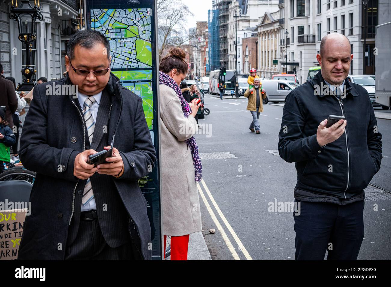 London, Großbritannien. 15. März 2023. Passanten schauen sich ihre iPhones an, während die Demo zum Budget Day vorbeizieht. Demonstranten bei der größten Demonstration seit Beginn der Streiks. Stockfoto