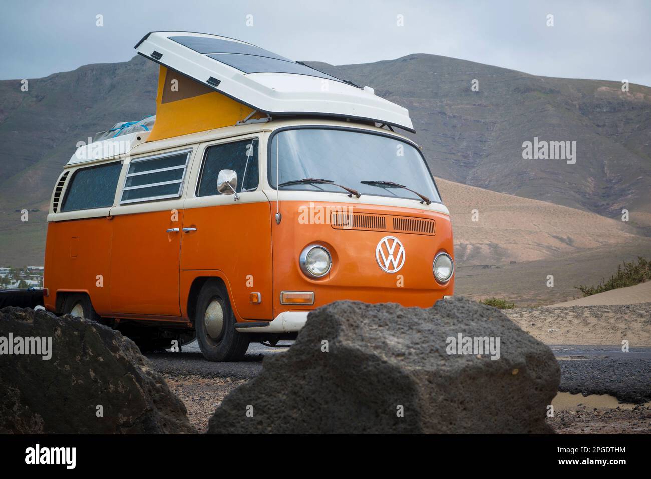 Famara, Lanzarote, März 2023, Illustrative Editorial: Blick auf den klassischen orangefarbenen Volkswagen T2 Wohnwagen Stockfoto