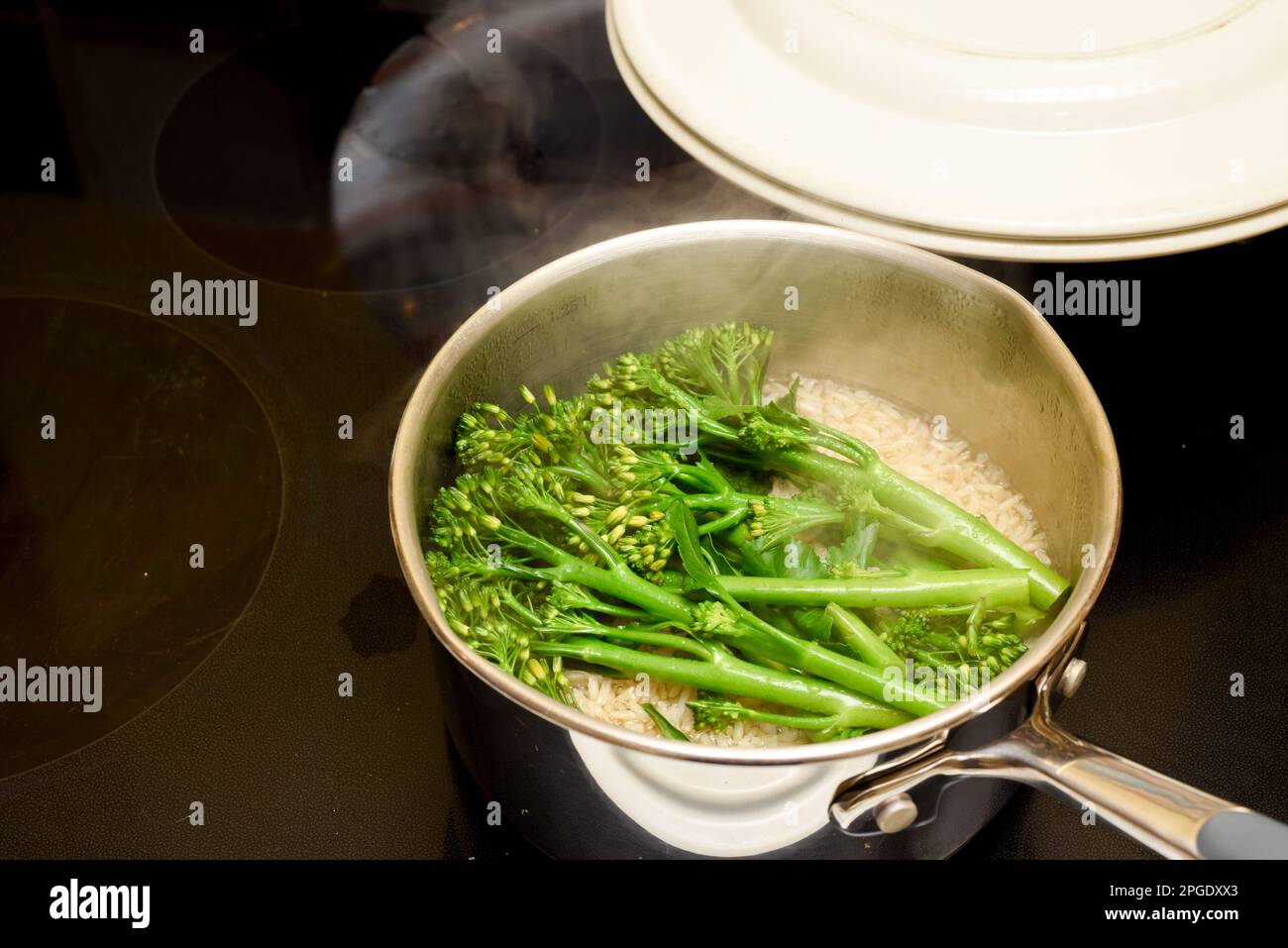 Dampfende Lebensmittel in der Pfanne Brokkoli und Reis kochen für eine gesunde Ernährung Stockfoto