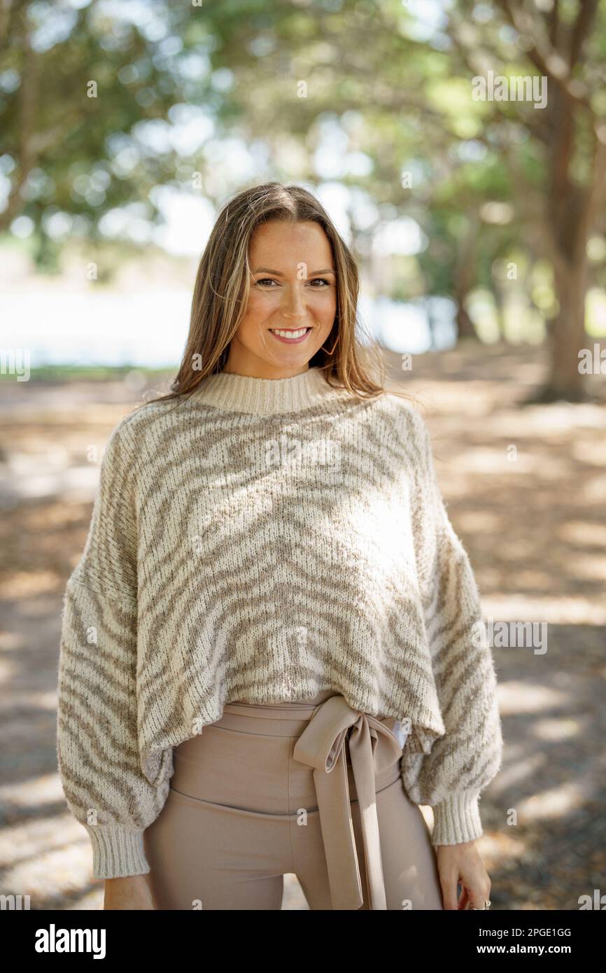 Schöne junge Frau, die im Park einen Pullover mit Tiermuster posiert Stockfoto