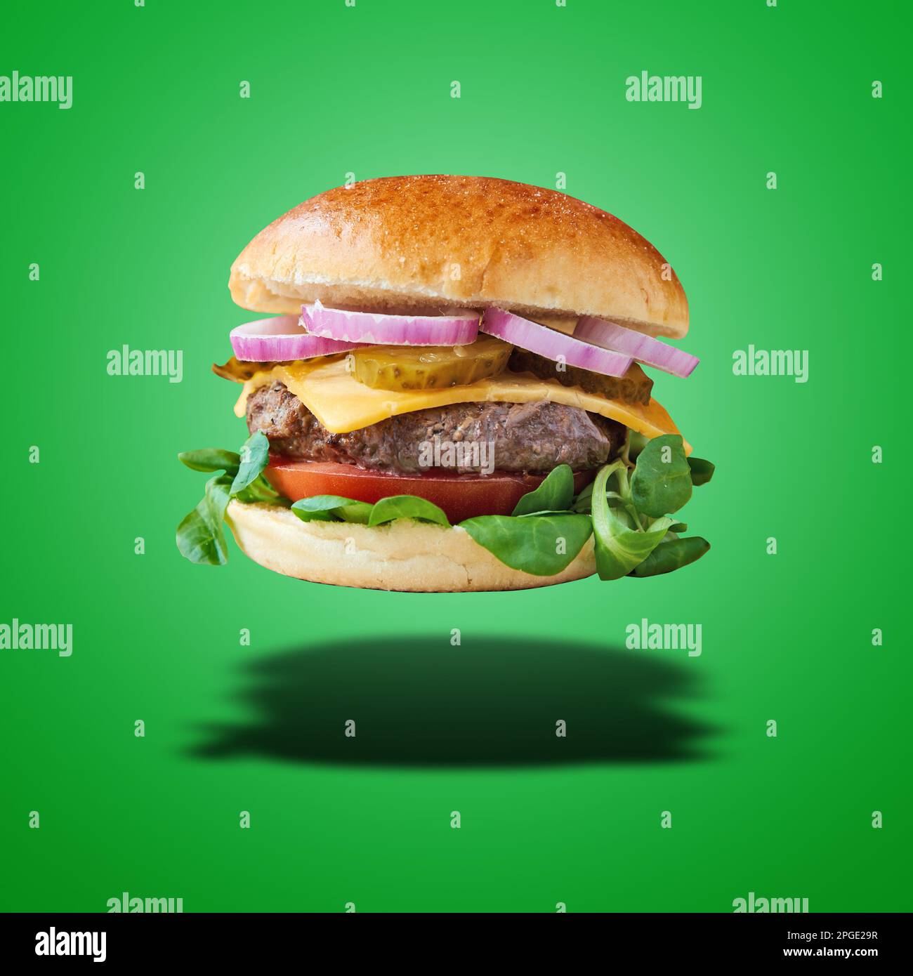 Schwimmender Burger mit Rinderzwiebeln und Käse auf grünem Hintergrund Stockfoto