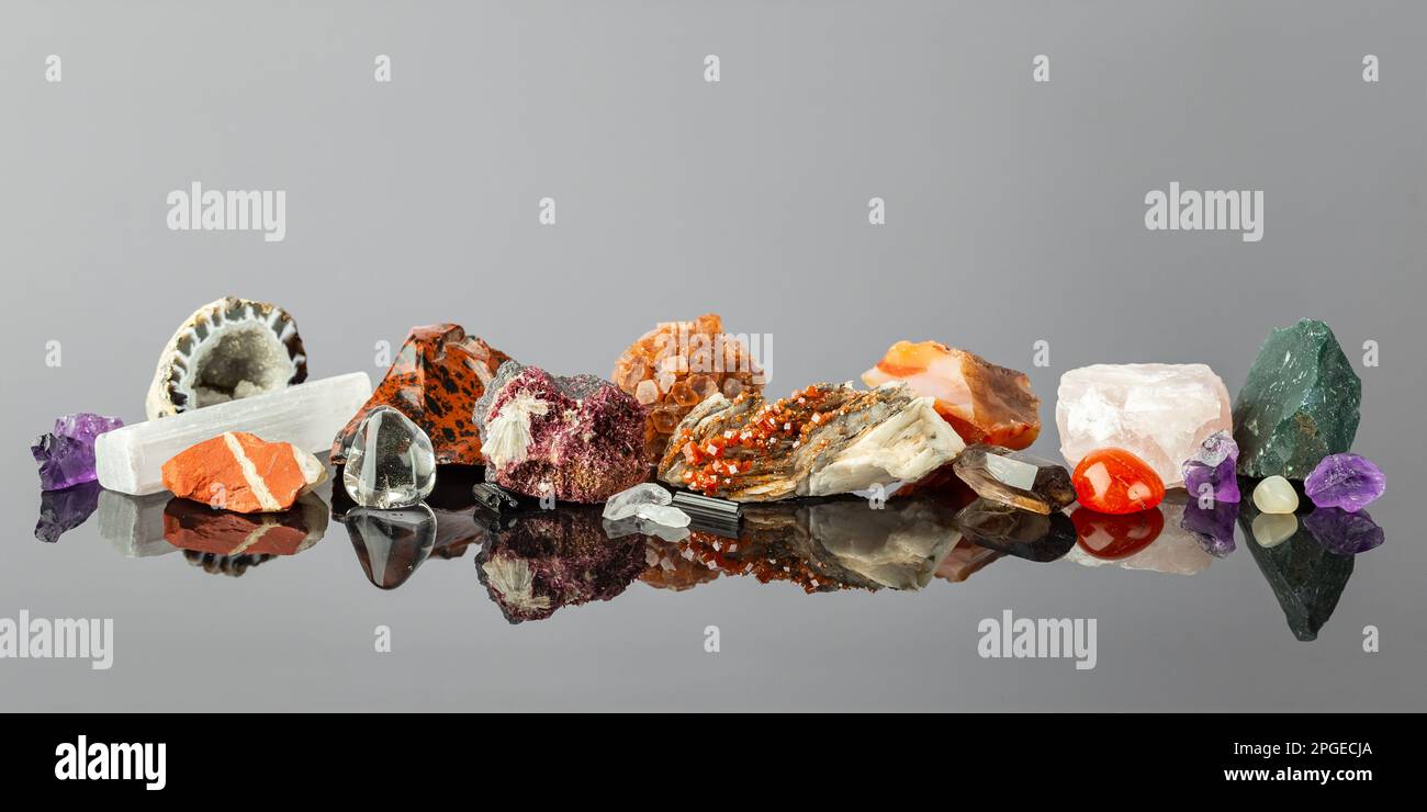 Breites Banner mit einer Gruppe bunter Steine und Mineralien, die in einer Reihe auf der reflektierenden Oberfläche angeordnet sind. Das Crystal Collector -Display Stockfoto