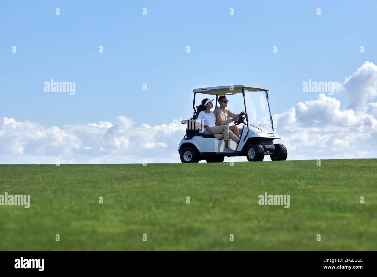 Minimales Hintergrundbild eines sportlichen Paares, das einen Golfwagen quer über das Feld fährt, mit Horizont in der Mitte, Kopierbereich Stockfoto