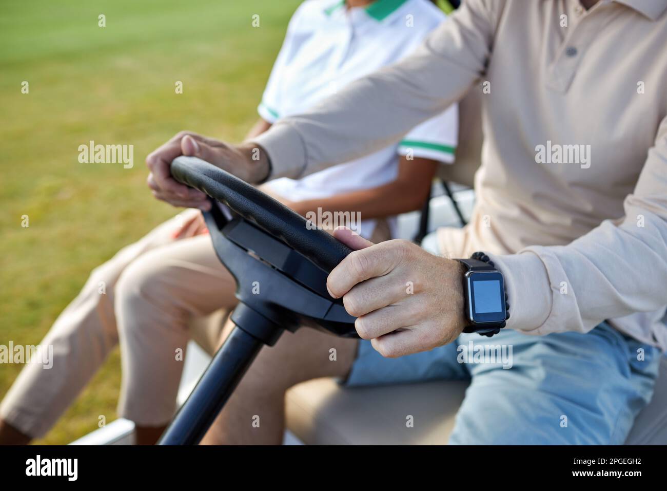 Nahaufnahme eines unbekannten reichen Mannes, der einen Golfwagen fährt, mit Fokus auf Hände, die das Rad halten, Kopierraum Stockfoto