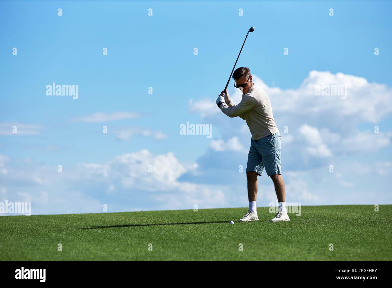 Porträt des aktiven, sportlichen Golfschlägers auf dem Spielfeld vor blauem Himmel, Kopierraum Stockfoto