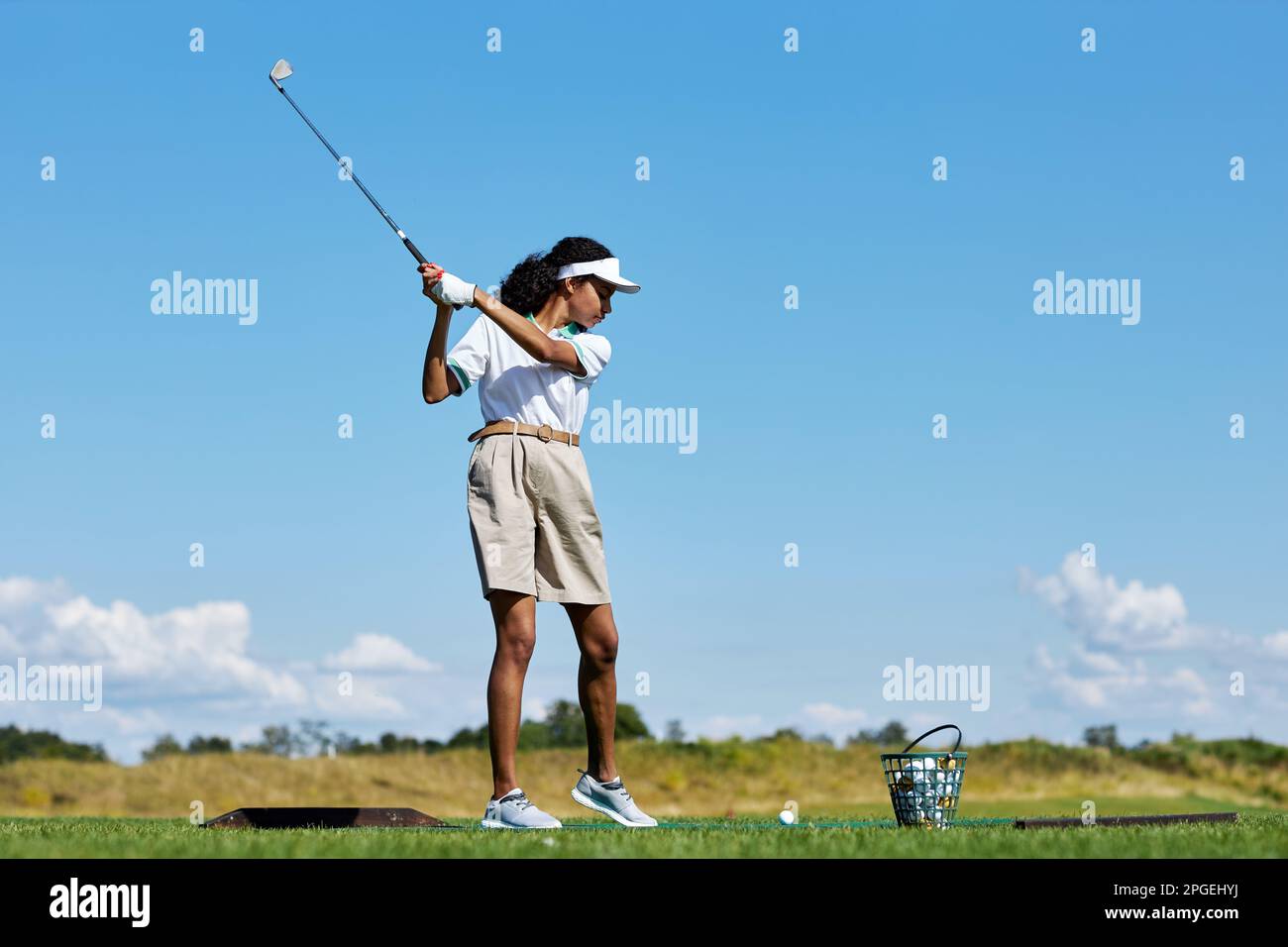 Seitliches Porträt einer sportlichen Frau, die im Freien Golf auf grünem Gras spielt, und schaukelnden Golfschläger, Kopierbereich Stockfoto