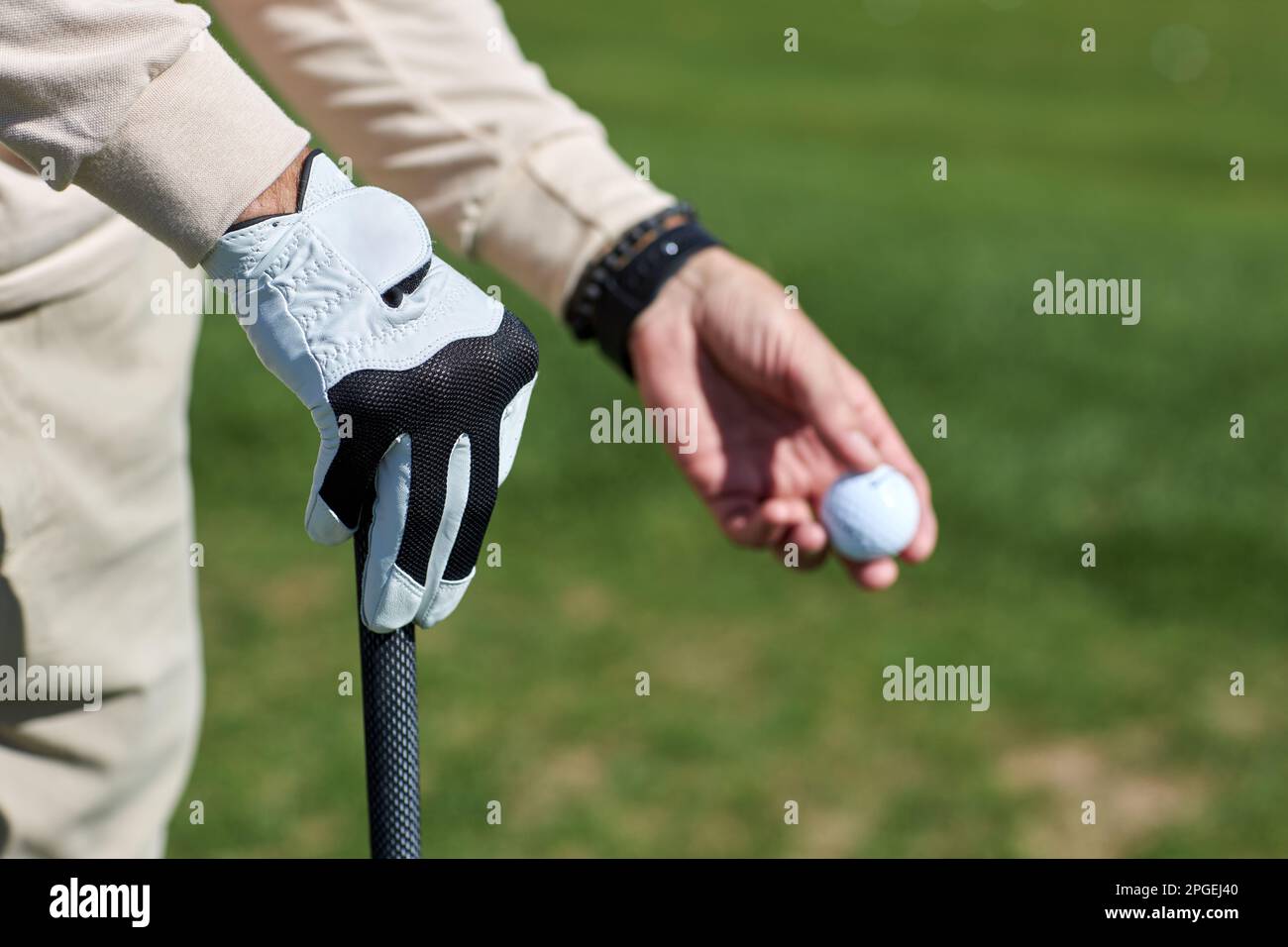 Nahaufnahme von männlicher Hand, die den Golfball im Freien gegen grünes Gras hält, Kopierbereich Stockfoto