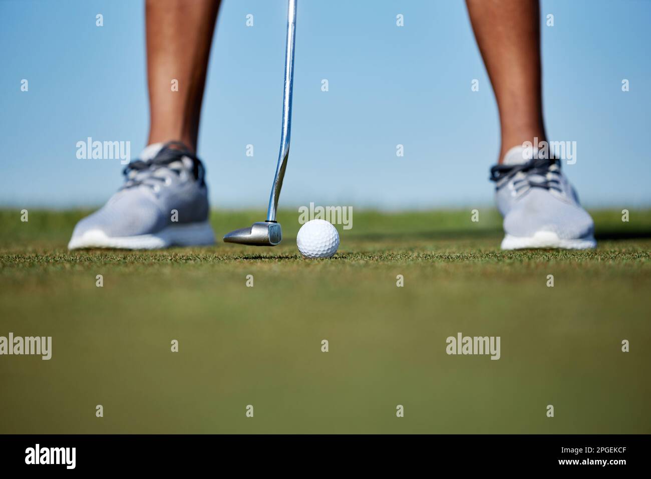 Makroaufnahme einer unbekannten Person, die Golf spielt und sich darauf konzentriert, dass der Golfschläger den Ball auf dem Gras schlägt Stockfoto