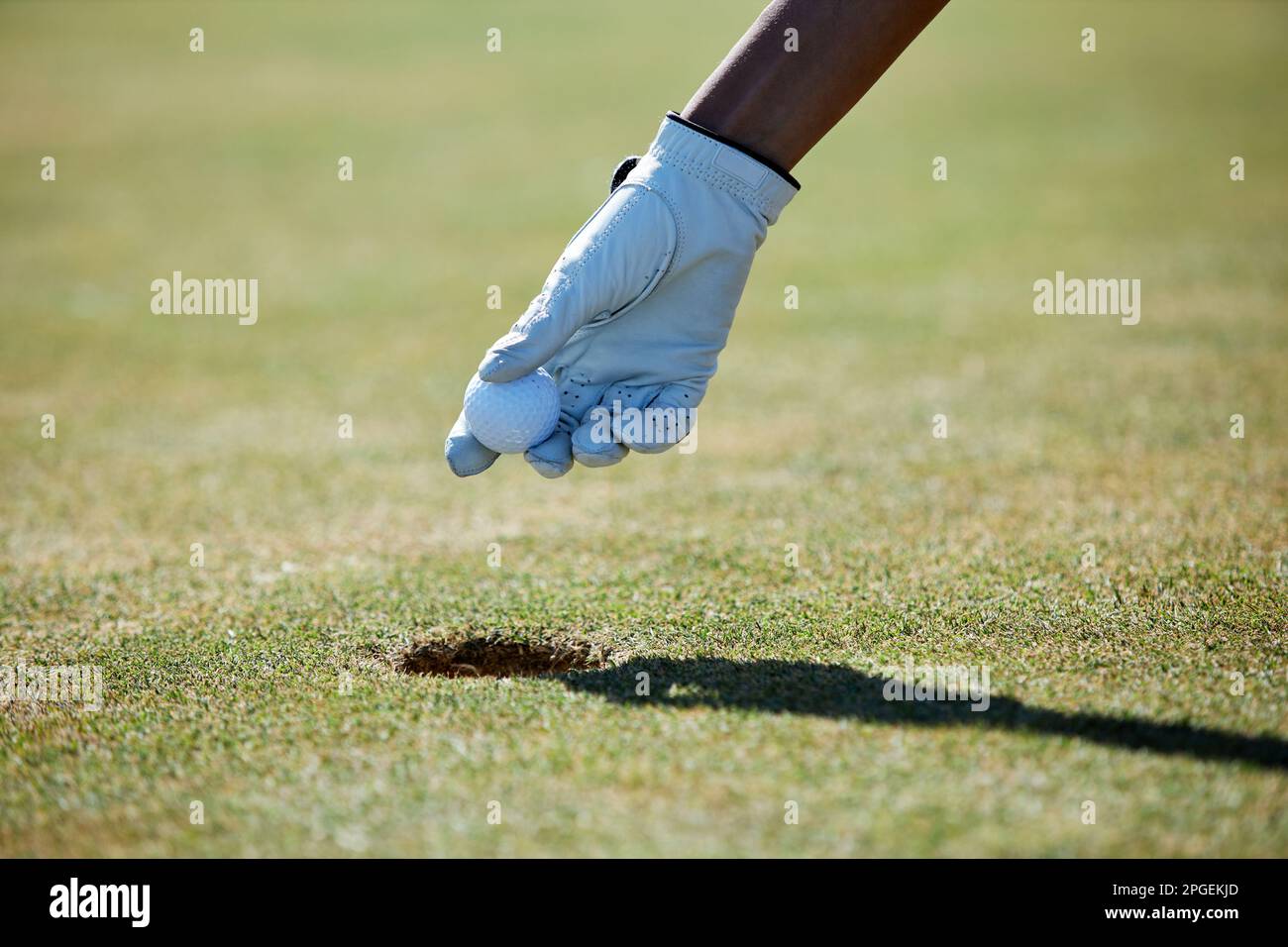 Nahaufnahme der Handschuhhand, die den Golfball aus dem Loch nimmt, Kopierbereich Stockfoto