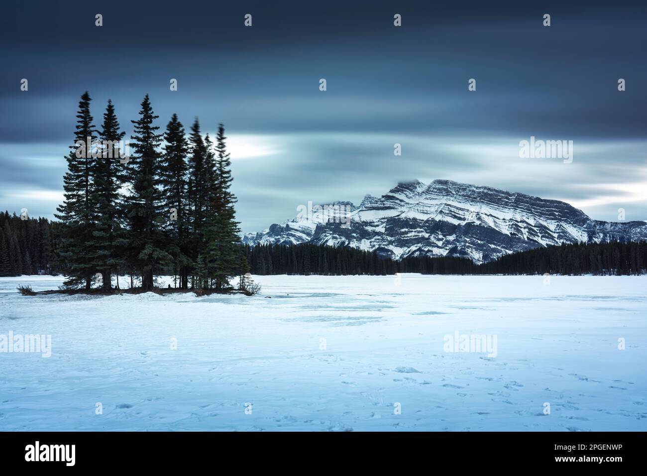 Am Abend im Banff National Park, Alberta, Kanada, bietet sich ein spektakulärer Blick auf Two Jack Lake mit Mount Rundle und Pinienwald im Winter Stockfoto
