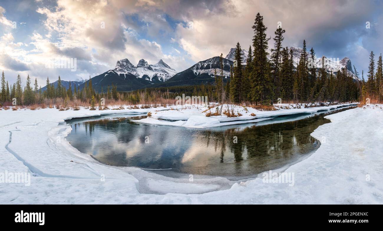 Wunderschöner Panoramablick auf die Three Sisters Mountains mit schneebedeckten Bug River Reflection am Morgen im Winter in Canmore, Alberta, Kanada Stockfoto