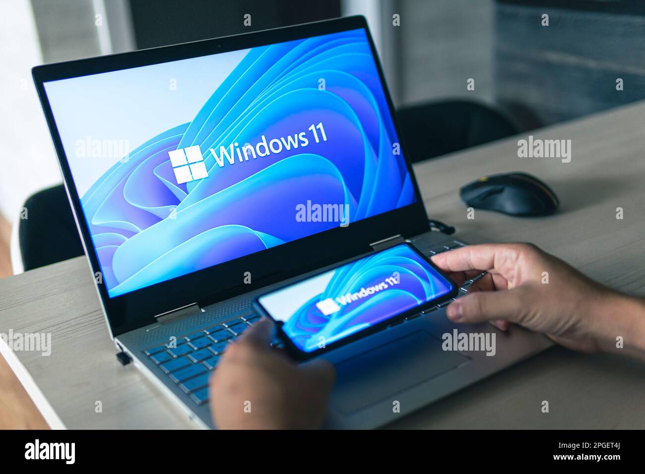 23. Juni 2021. Barnaul, Russland. Mann mit einem Laptop und einem Smartphone, Windows 11 neues Microsoft-Betriebssystem auf den Bildschirmen Stockfoto