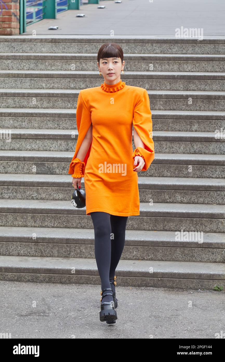 MAILAND, ITALIEN - 24. FEBRUAR 2023: Frau mit orangefarbenem Kleid und schwarzen Strümpfen vor der Sportmax-Modenschau, Mailand Fashion Week Street Style Stockfoto