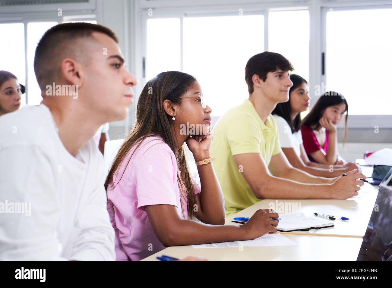 Afroamerikanische Studentin, die eine Vorlesung hört, während sie einen Kurs im Klassenzimmer besucht. Multiethnische Gruppe junger High-School-Colleges Stockfoto