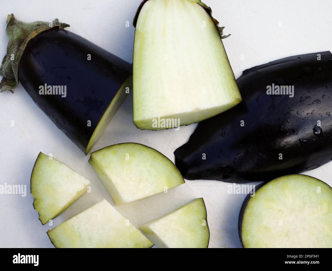 Stücke einer Aubergine auf einem weißen Schneidebrett Stockfoto