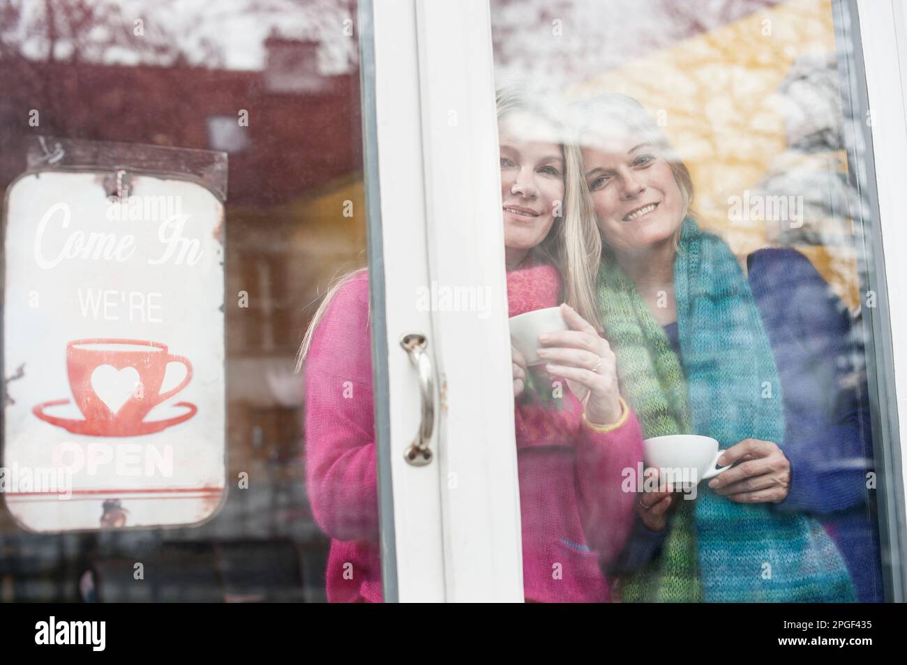 Zwei Freunde, die durch das Fenster schauen und Kaffee trinken in einem Café, Bayern, Deutschland Stockfoto