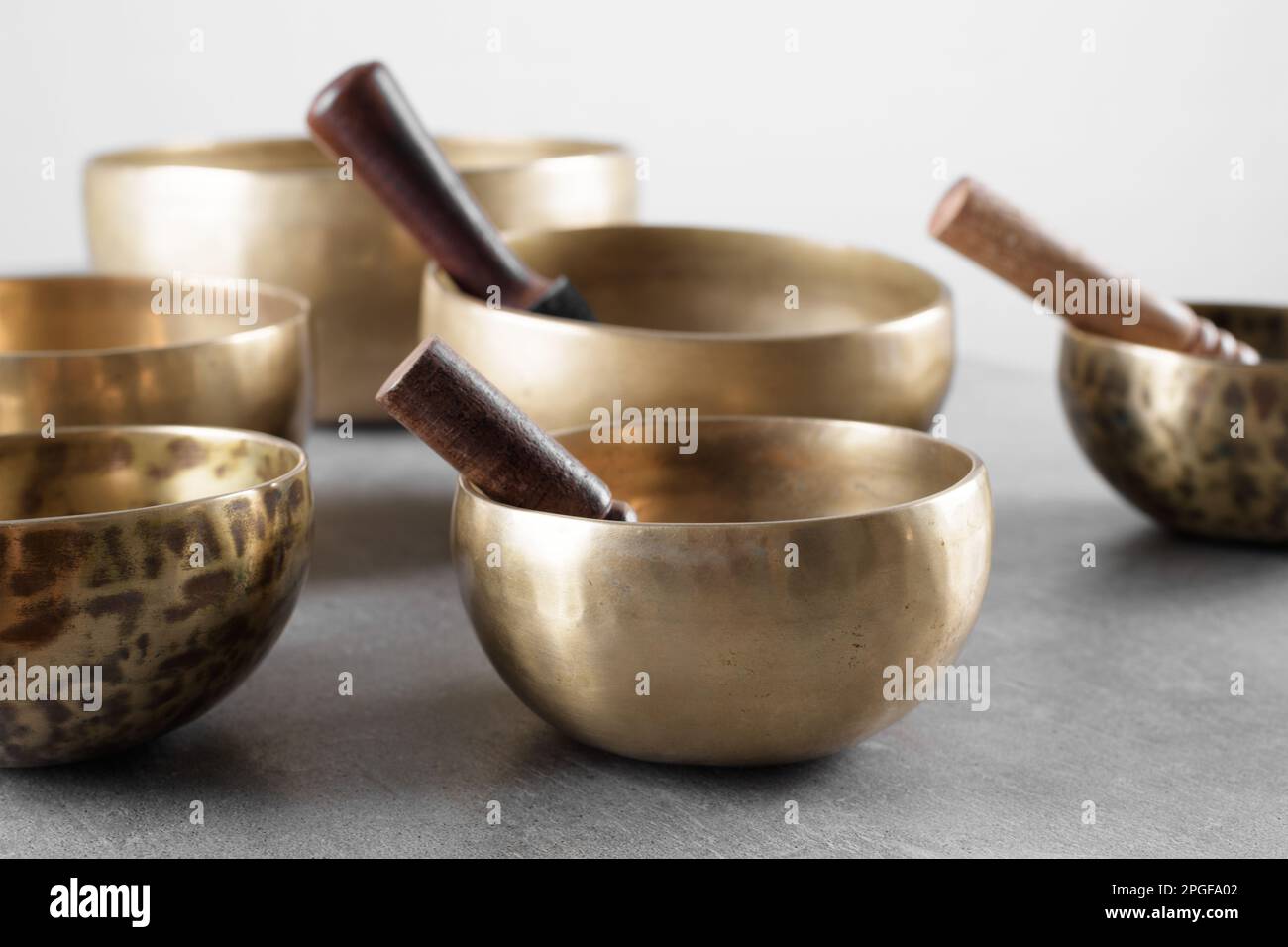 Tibetische Gesangsschüsseln mit Stöcken für Mantra-Meditationen auf grauem Stein Stockfoto