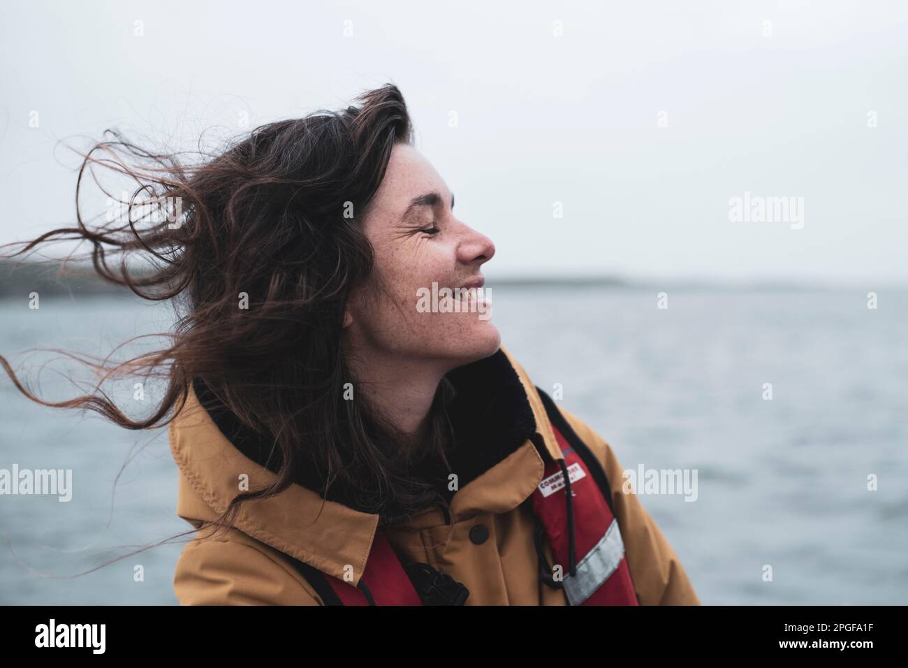 Profil einer glücklichen Frau mit Sommersprossen, die auf einem Boot in Schottland lächelt Stockfoto