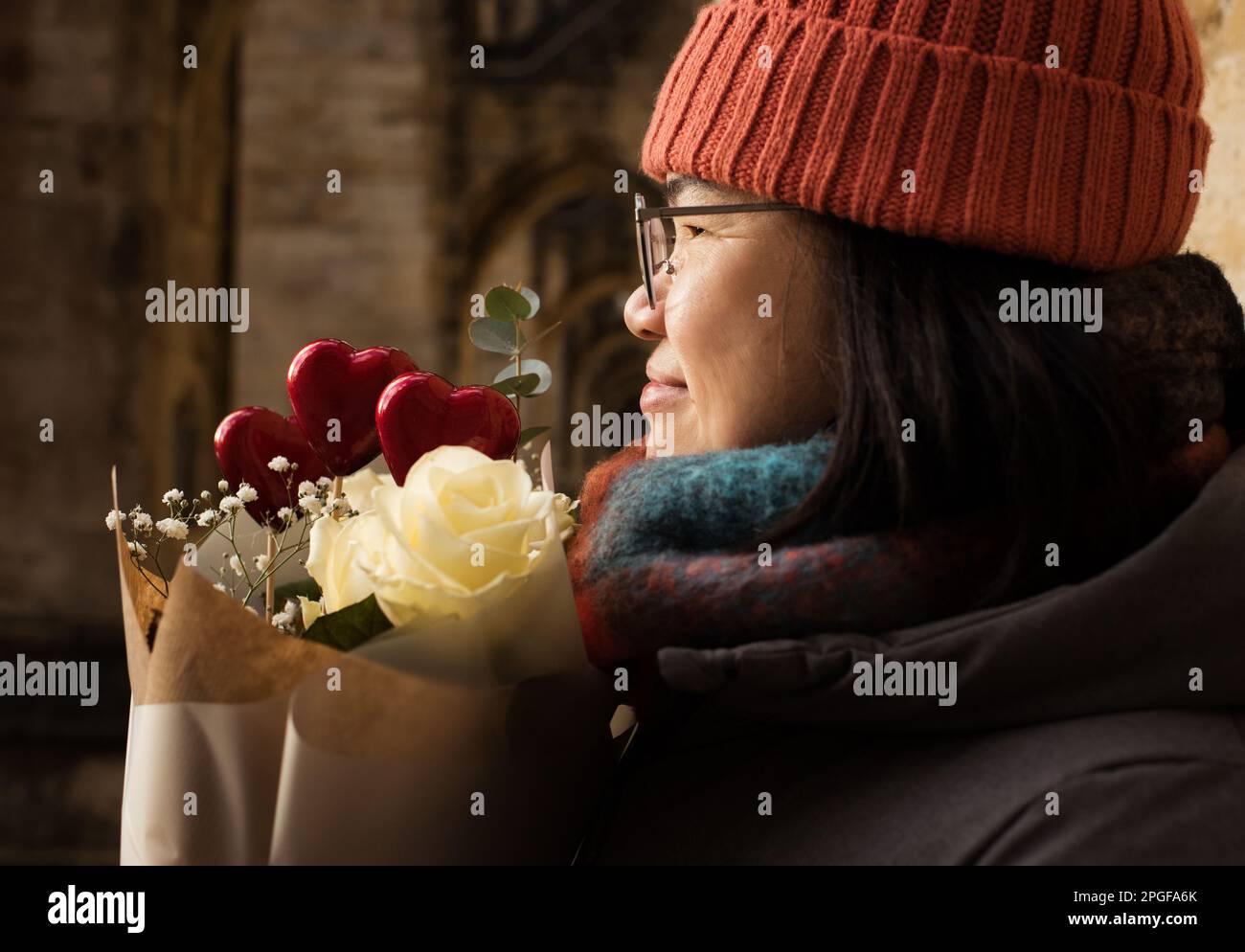 Asiatische Frau, die Blumen und rote Herzen zum Valentinstag in der Hand hält Stockfoto