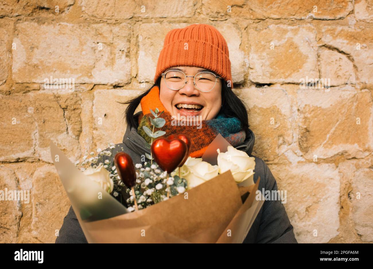 Fröhliches Porträt einer Asiatin, die mit Valentinsblumen lächelt Stockfoto