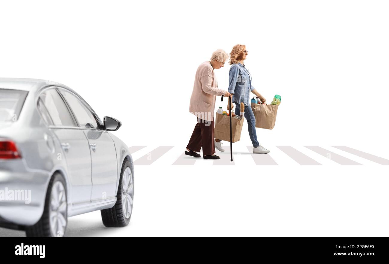 Ein Auto fährt auf einen Fußgängerübergang zu, eine Frau mit einer älteren Dame überquert die Straße und trägt Einkaufstaschen isoliert auf weißem Hintergrund Stockfoto