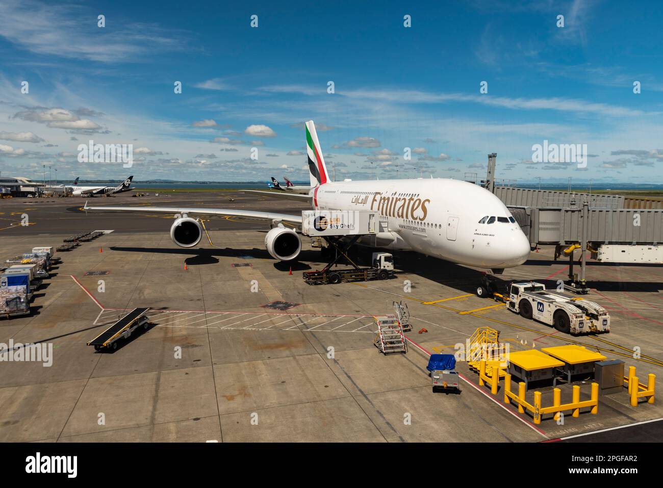 Emirates A380 Flugzeug Jet Flugzeug A6-EVR am Stand am Auckland Flughafen, Neuseeland. Verbunden mit Luftbrücke mit Schlepper und Beladung der LSG Sky Chefs Stockfoto