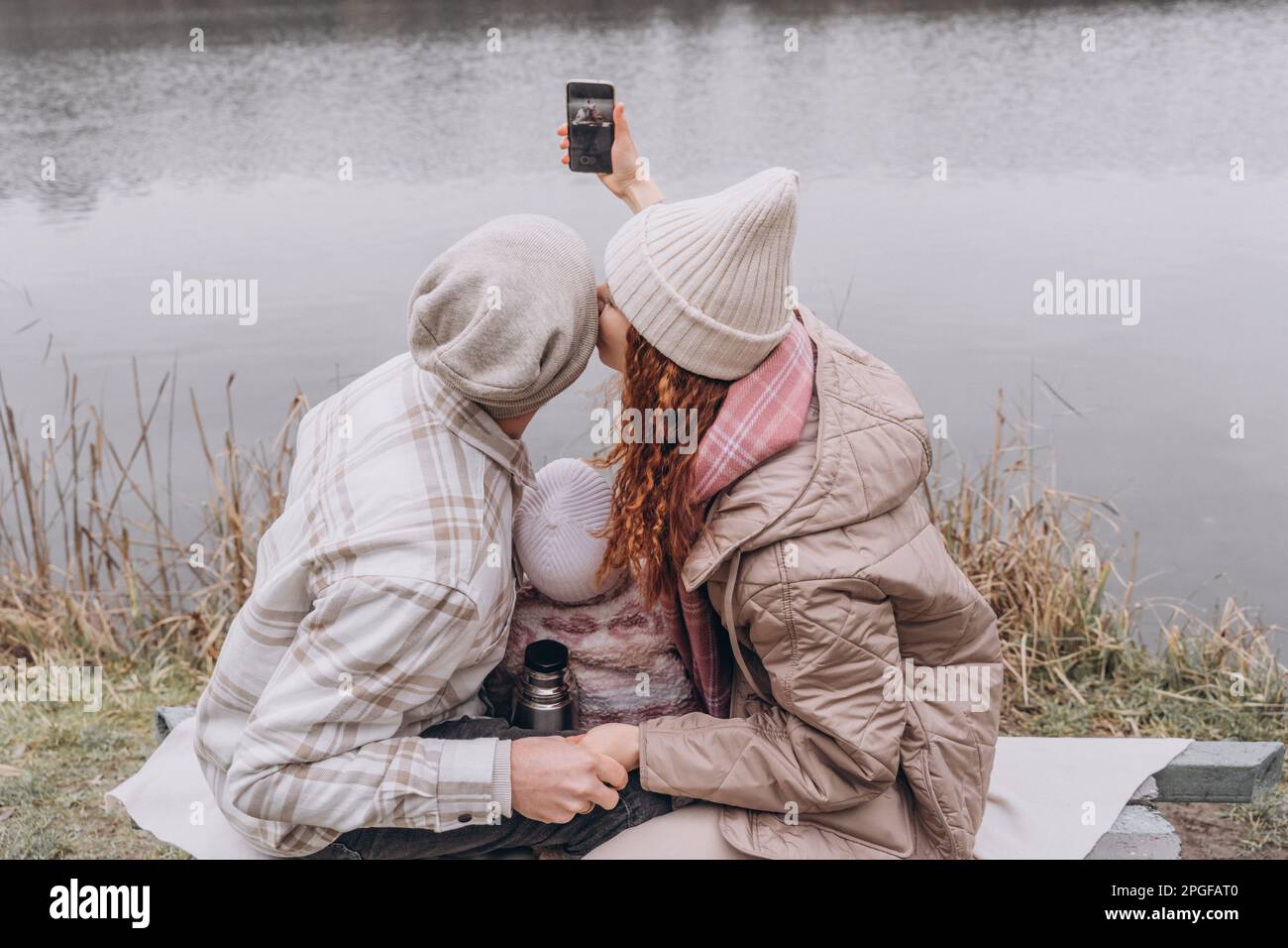 Eine Familie mit einem kleinen Kind ruht bei kaltem Wetter am Fluss Stockfoto