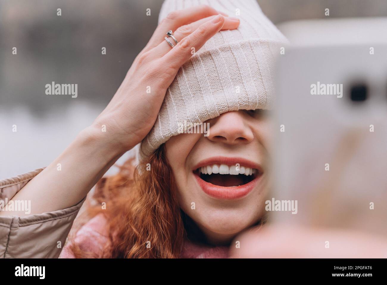 Lockige rothaarige Frau 30-35 mit einem Hut über den Augen macht Selfie Stockfoto