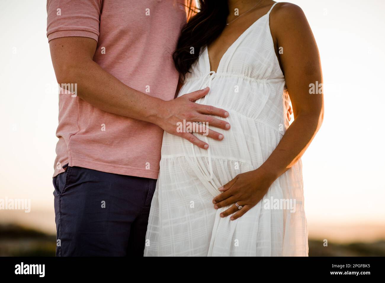 Nahaufnahme der Hand des Ehemanns auf der Baby Bump seiner Frau in San Diego Stockfoto