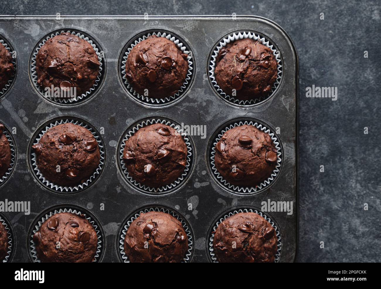 Über dem Kopf eine Dose Schokoladenzucchini-Muffins auf schwarzem Hintergrund. Stockfoto