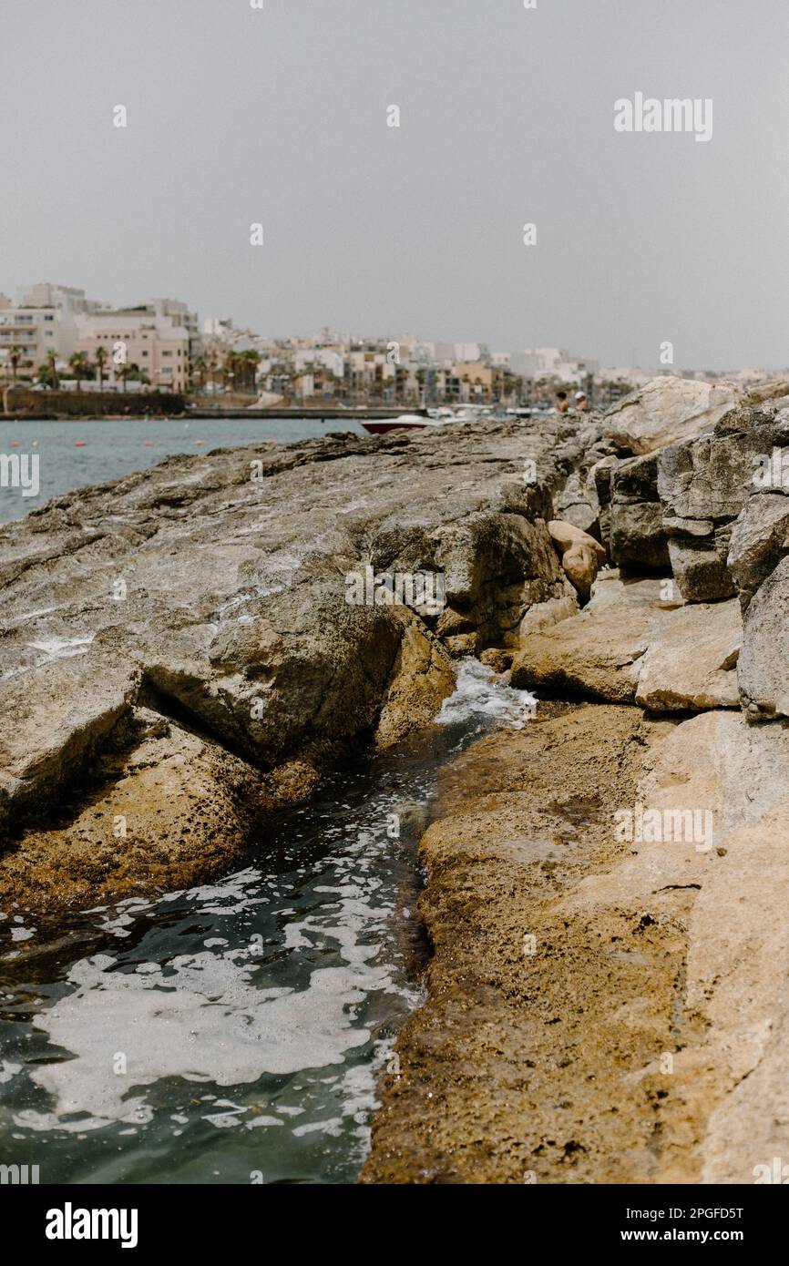 Wellen stürzen auf große Felsen an einem Strand in Malta Stockfoto