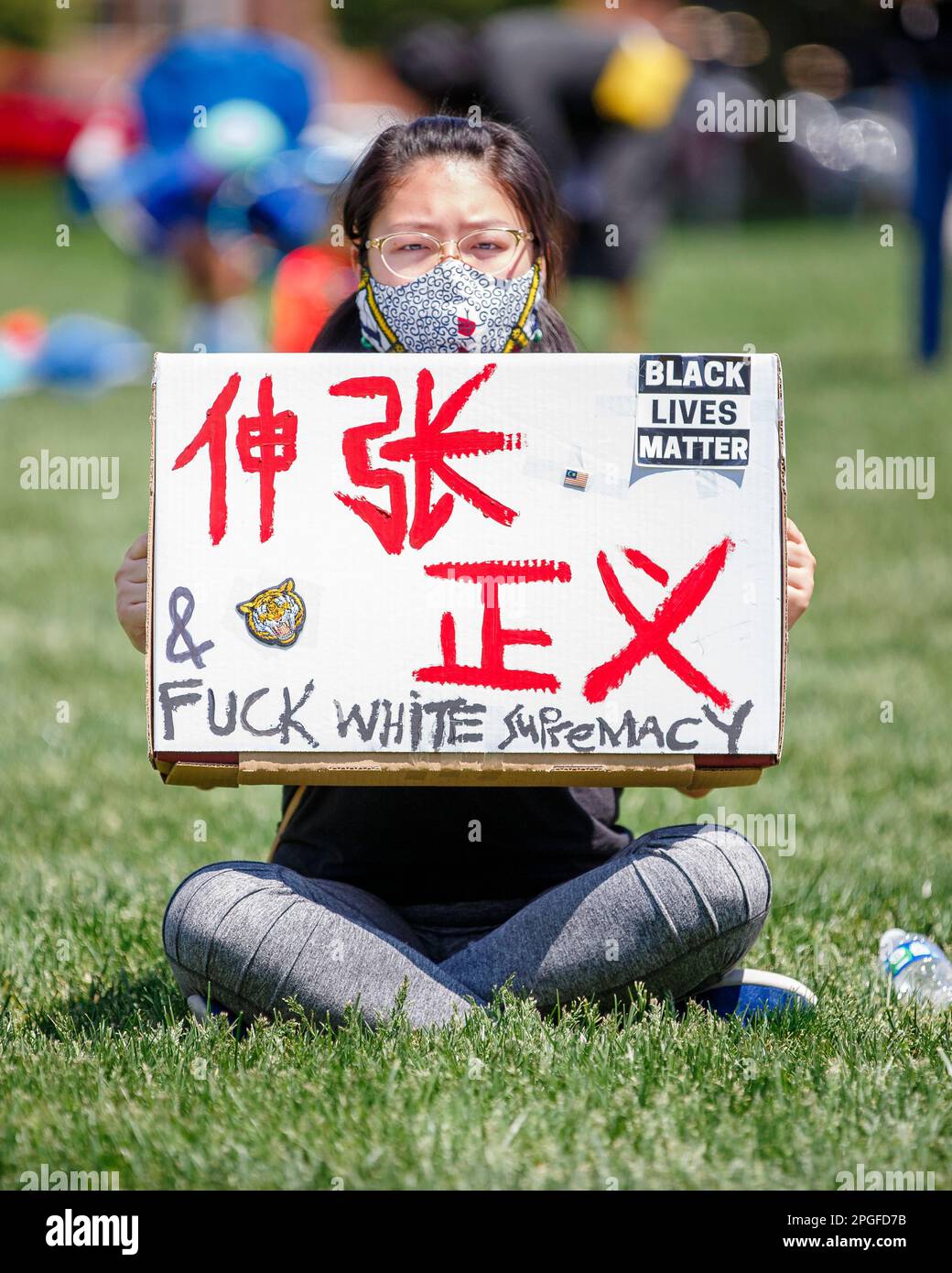 Eine junge Frau mit Maske hält ein Protestzeichen gegen Rassismus Stockfoto