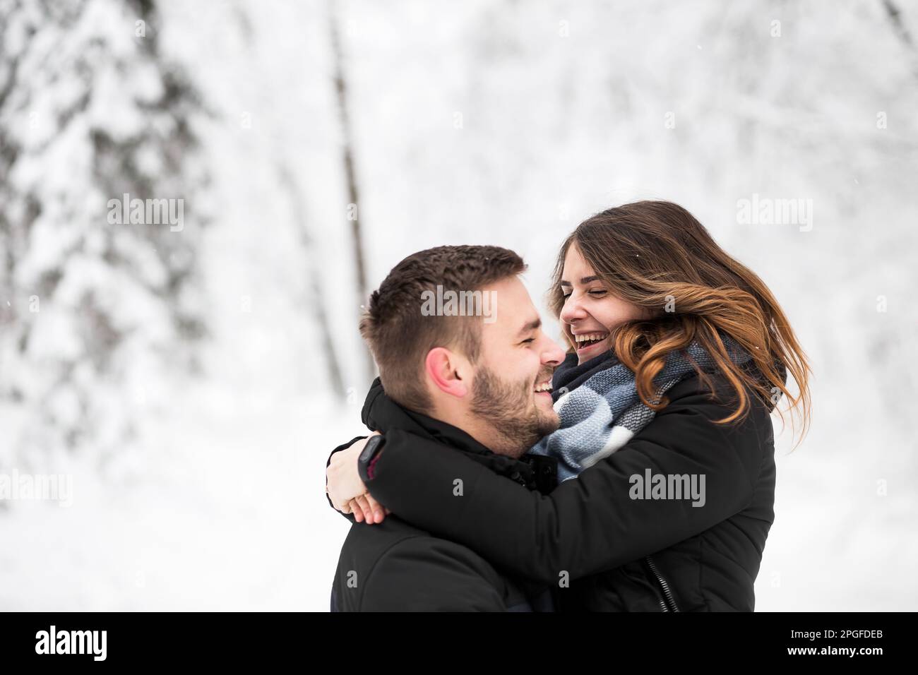 Ein Paar, das Spaß im Winterpark hat und lacht Stockfoto
