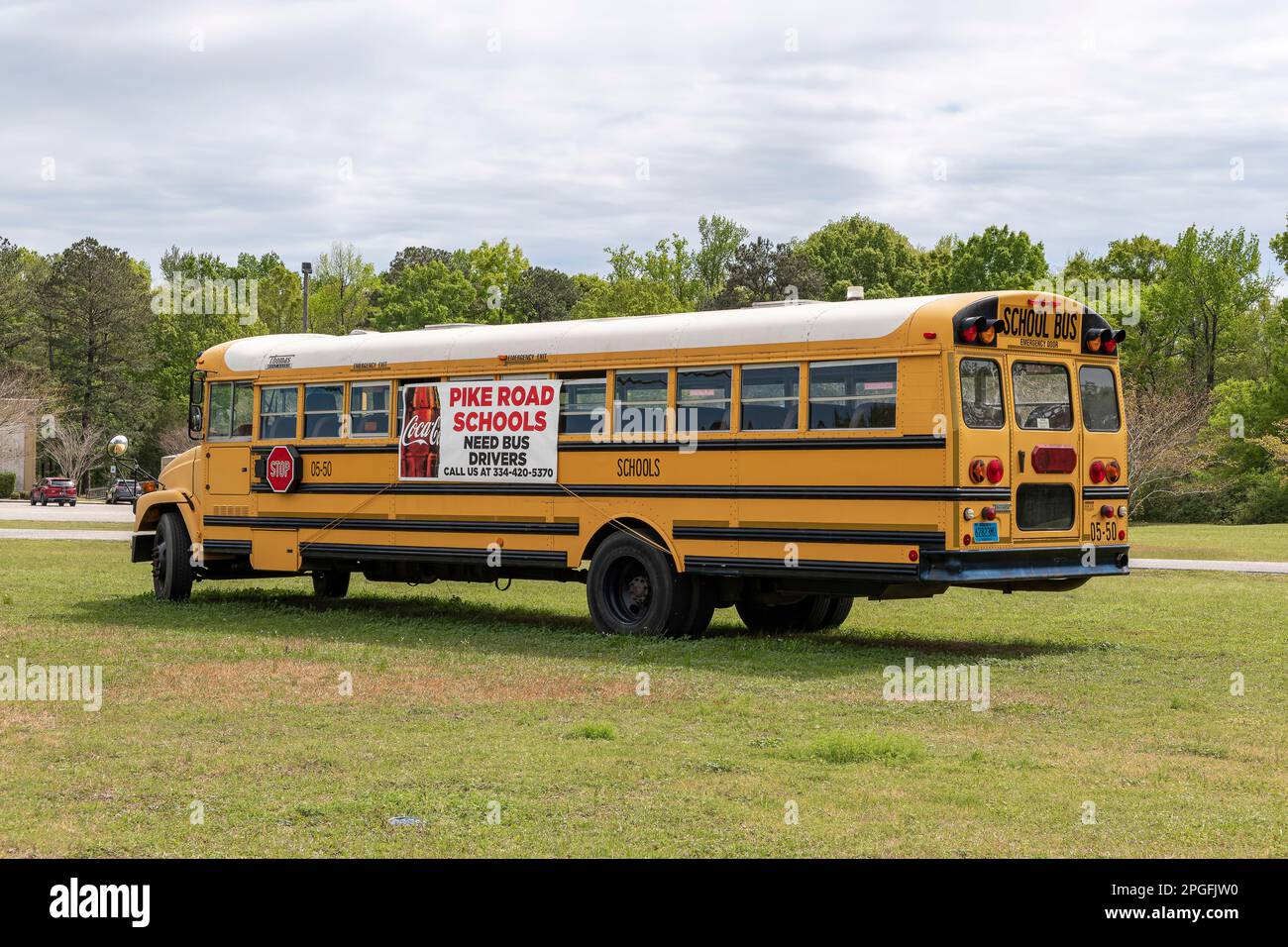 Geparkter Schulbus mit Fahrer gesucht oder Hilfe gesucht Schild an der Seite der Buswerbung für Schulbusfahrer in Pike Road, Alabama, USA. Stockfoto