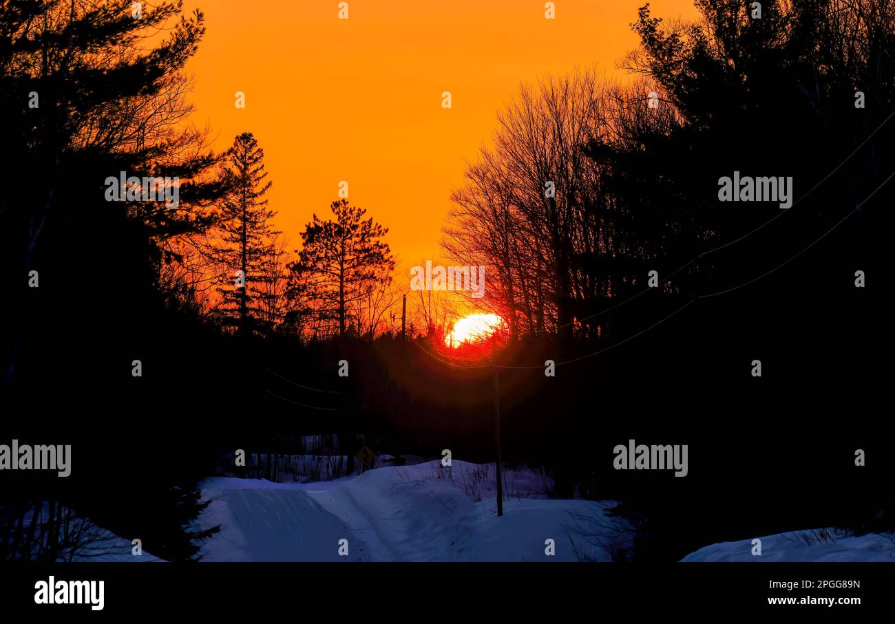 Der Sonnenuntergang auf einer ländlichen Winterstraße im Norden von Wisconsin. Stockfoto