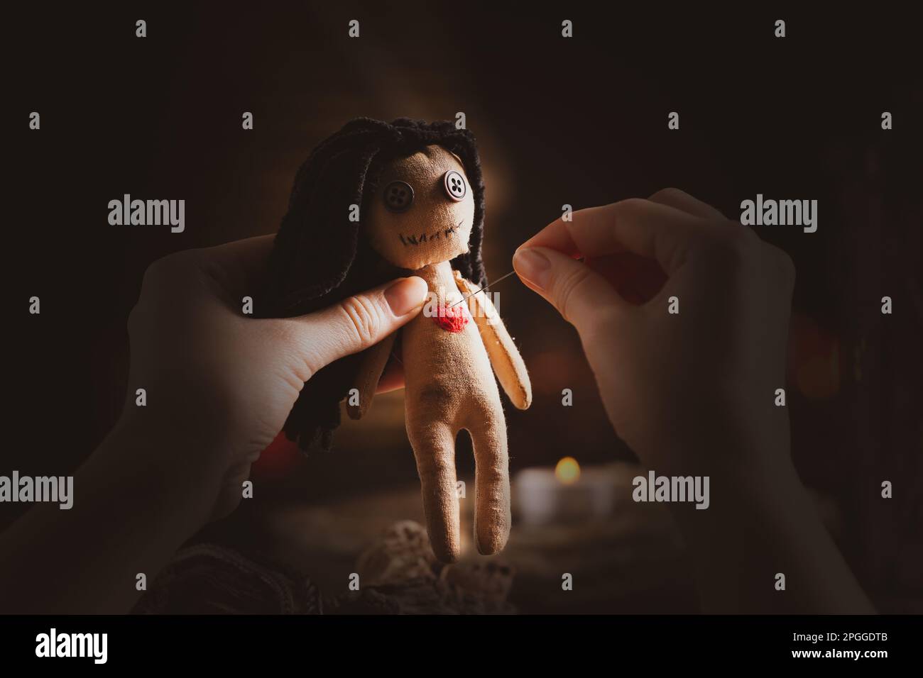Eine Frau, die das Herz einer Voodoo-Puppe stach, mit einer Nadel am Tisch, Nahaufnahme Stockfoto
