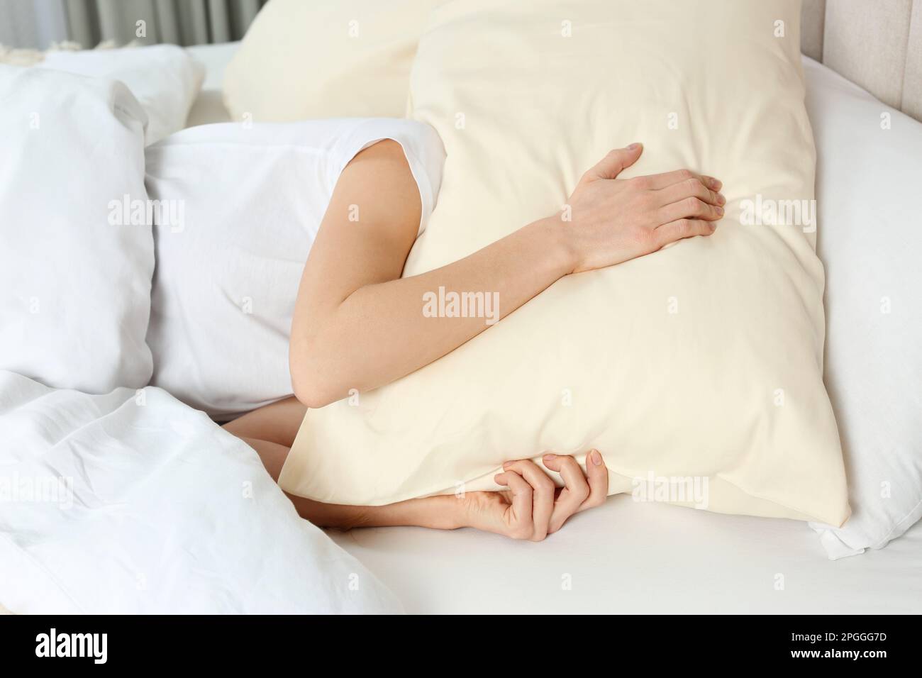 Schlaflose Frau, die zu Hause den Kopf mit einem Kissen im Bett bedeckt Stockfoto
