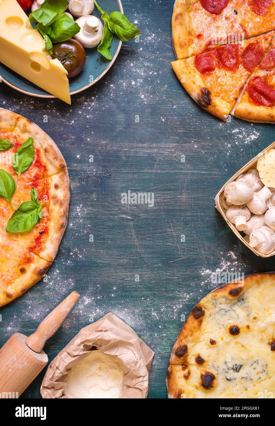 Pizza mit verschiedenen Belägen und Zutaten. Platz für Text. Pizza, Mehl, Käse, Tomaten, Basilikum, Peperoni, Pilze und Walznadel Stockfoto