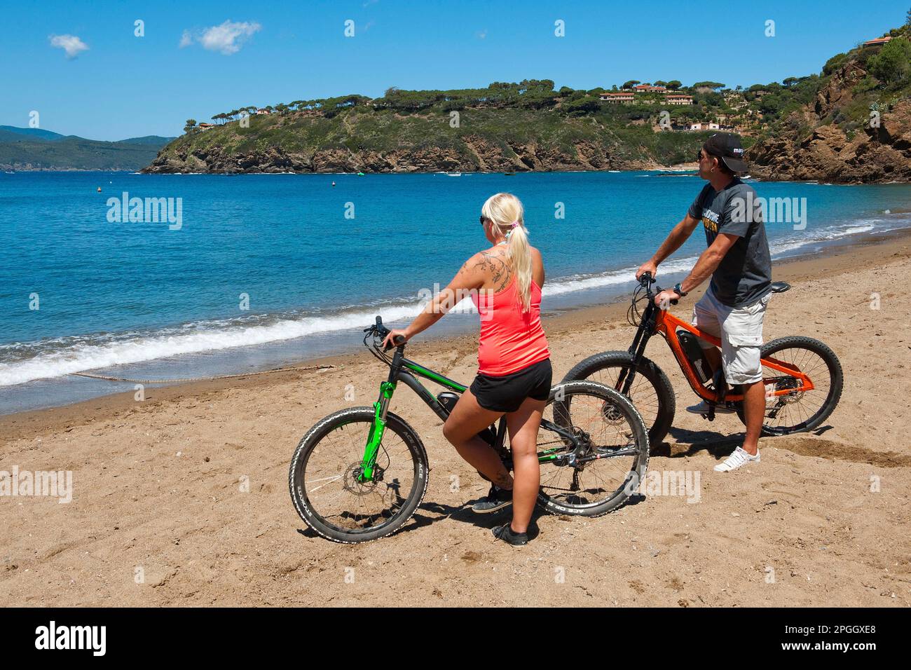 Ein Paar mit Elektrofahrrädern am Strand, Europa, Morcone, Elba, Toskana, Italien Stockfoto